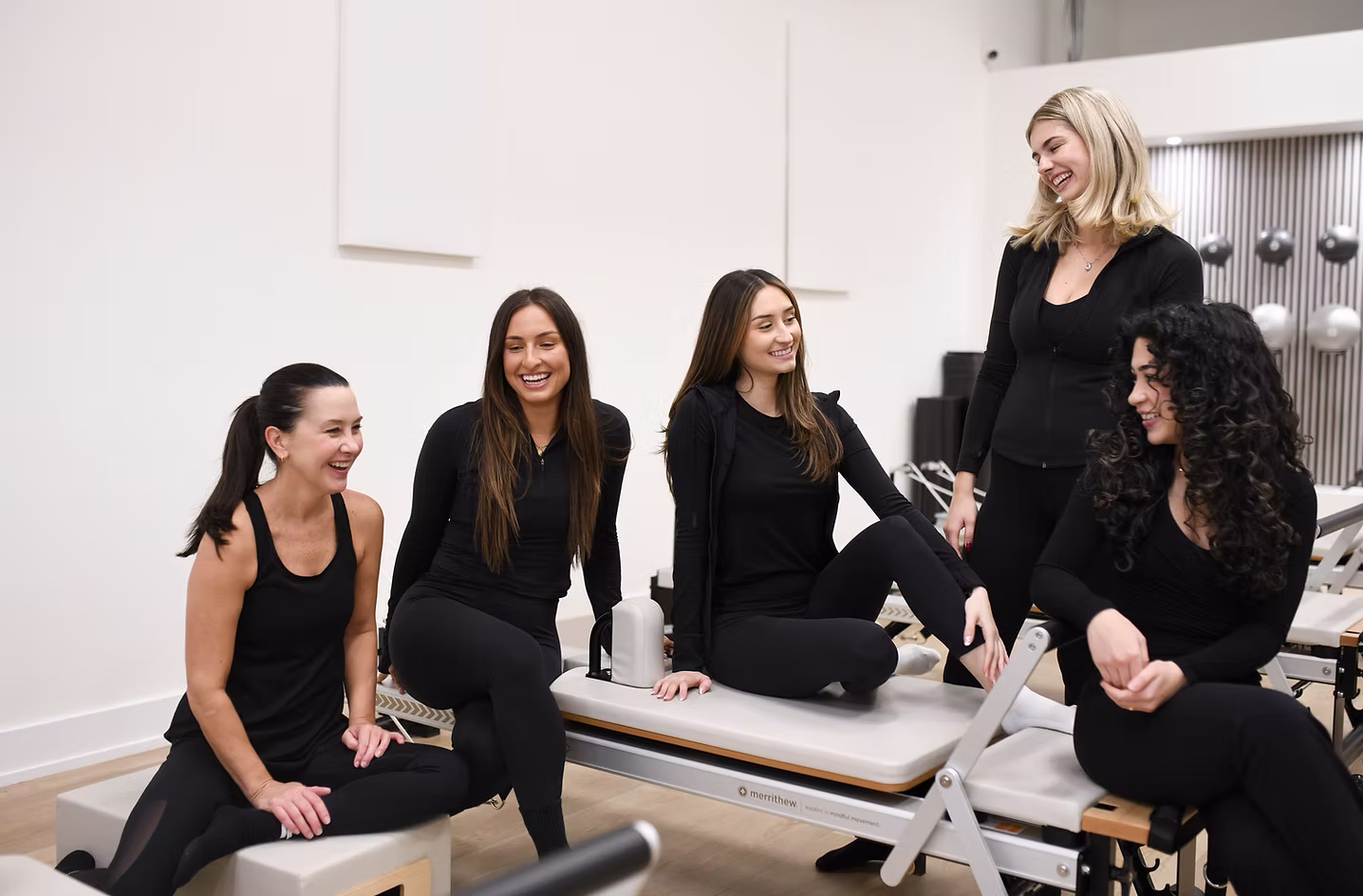 Revity Pilates instructors laughing together on reformers at the Burlington studio